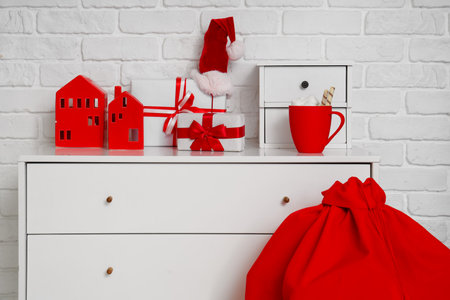 Christmas gifts with cocoa and candle holders on chest of drawers in roomの写真素材