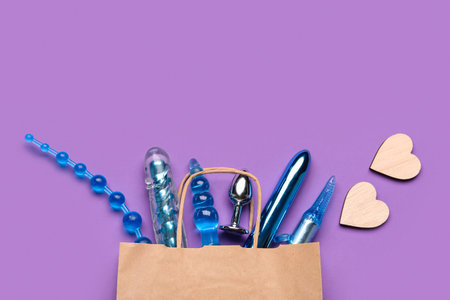 Shopping bag with sex toys and paper hearts on purple backgroundの写真素材