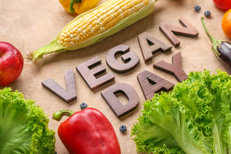 Text VEGAN DAY with fresh vegetables and fruits on beige background