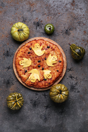 Wooden board with tasty pizza and decorations for Halloween party on grunge backgroundの写真素材