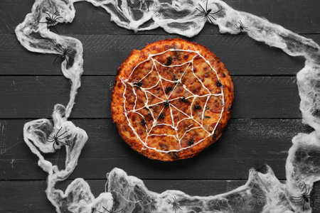 Tasty pizza and spiders for Halloween party on black wooden backgroundの写真素材