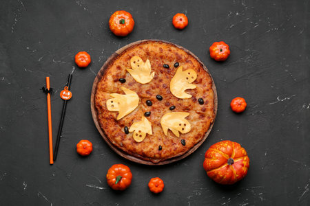 Wooden board with tasty pizza and pumpkins for Halloween party on black backgroundの写真素材