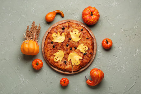 Wooden board with tasty pizza and pumpkins for Halloween party on gray backgroundの写真素材