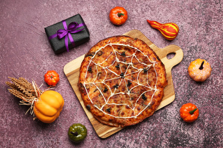 Wooden board with tasty pizza and decorations for Halloween party on purple backgroundの写真素材