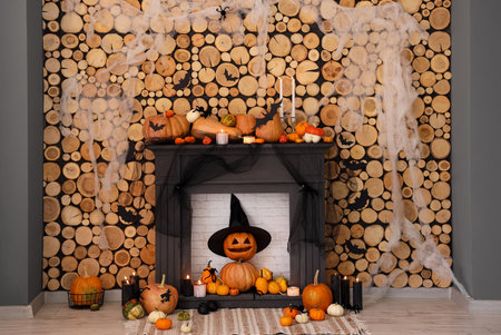 Fireplace with Halloween pumpkins and decorations near wooden wallの写真素材