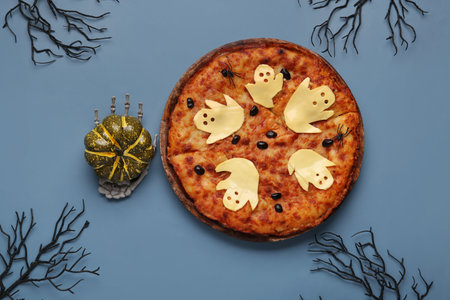 Wooden board with tasty pizza and decorations for Halloween party on blue backgroundの写真素材