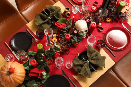 Festive table setting with Halloween pumpkins, burning candles and leaves