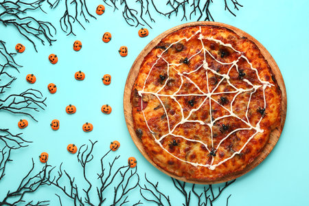 Wooden board with tasty pizza and decorations for Halloween party on blue backgroundの写真素材