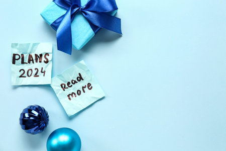 Sticky notes with goals for 2024, gift box and Christmas balls on blue background