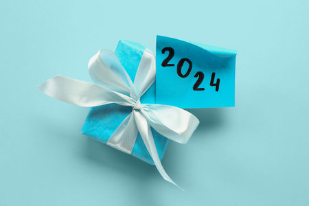 Sticky note with year 2024 and gift box on blue background