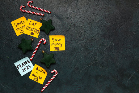 Sticky notes with different goals for 2024 and Christmas decorations on grunge black background