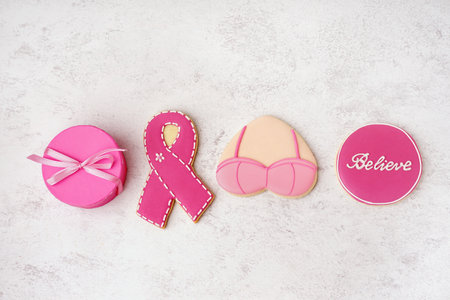 Pink cookies with ribbon, bra, word BELIEVE and gift box on white grunge background. Breast cancer awareness conceptの写真素材