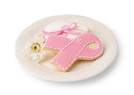 Plate with pink cookie in shape of ribbon and chrysanthemum flower isolated on white background. Breast cancer awareness conceptの写真素材