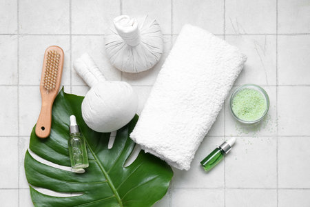 Composition with spa accessories, bottles of essential oil and palm leaf on light tile backgroundの写真素材