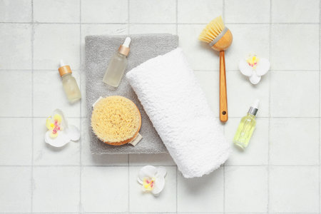 Composition with spa accessories, bottles of essential oil and orchid flowers on light tile backgroundの写真素材