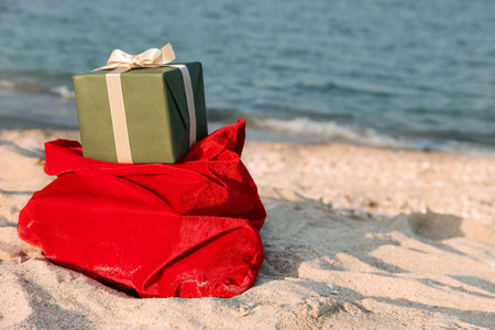Red Santa bag with gift box on sea beach. Christmas vacation conceptの写真素材