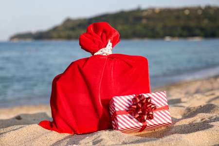 Santa bag and gift box on sea beach. Christmas vacation conceptの写真素材