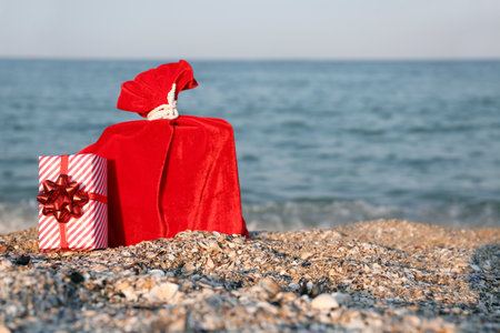 Red Santa bag and gift box on sea beach. Christmas vacation conceptの写真素材