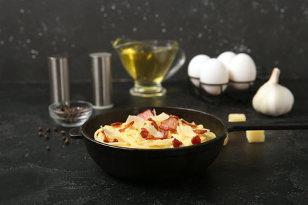 Frying pan with tasty pasta carbonara on black backgroundの写真素材