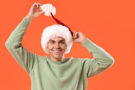 Happy young man in Santa hat on orange backgroundの写真素材