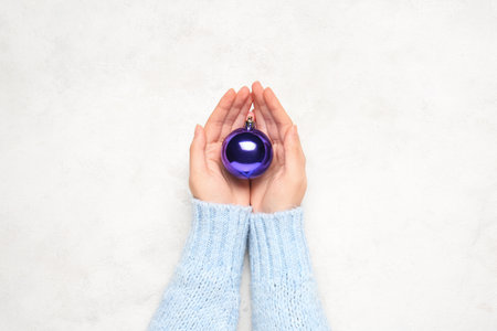Female hands with beautiful Christmas ball on light background, closeupの写真素材