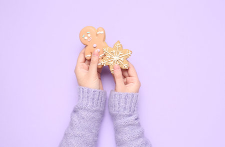 Female hands with sweet Christmas cookies on lilac background, closeupの写真素材