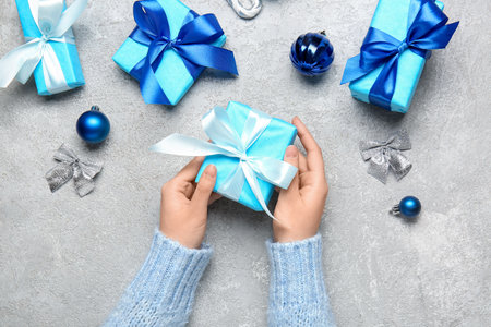 Female hands with beautiful Christmas gifts and decorations on grunge background, closeupの写真素材