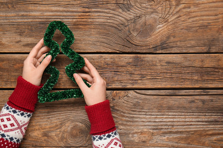 Female hands with decoration in shape of Christmas tree on wooden background, closeupの写真素材