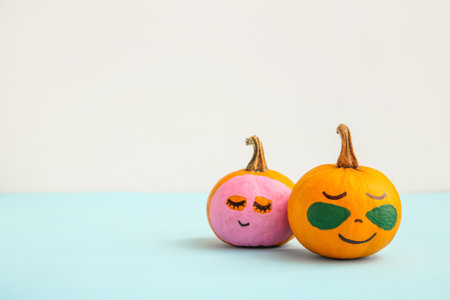 Pumpkins with mask and under-eye patches on blue tableの写真素材