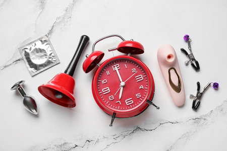 Alarm clock with different toys and condom on grunge white background. Time for sexの写真素材