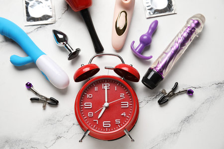 Alarm clock with different toys and condoms on grunge white background. Time for sexの写真素材