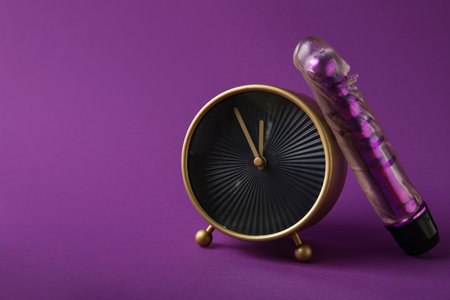 Alarm clock with vibrator on purple background. Time for sexの写真素材