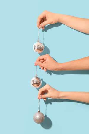 Female hands holding silver Christmas balls on blue background