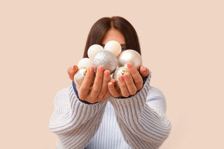 Woman holding silver Christmas balls on beige background, closeupの写真素材