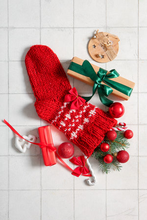 Christmas sock with tree branches, beautiful decorations and gift boxes on white tile backgroundの写真素材