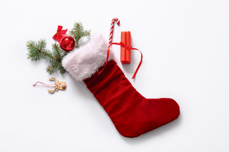 Christmas sock with tree branches, beautiful decorations and gift box on white background