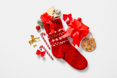 Christmas sock with beautiful decorations and gift boxes on white background