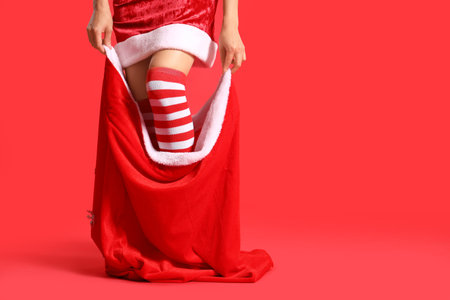 Young woman in Santa bag on red backgroundの写真素材