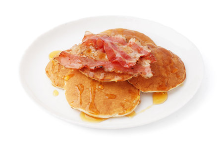 Plate of tasty pancakes with bacon and maple syrup on white backgroundの写真素材