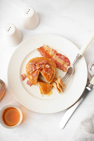 Plate of tasty pancakes with bacon and maple syrup on white backgroundの写真素材