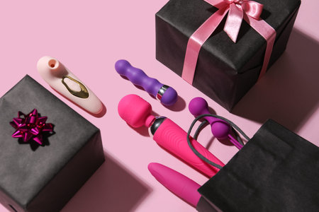 Bag with sex toys and gifts on pink background