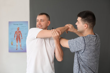 Mature man training with therapist in rehabilitation centerの写真素材