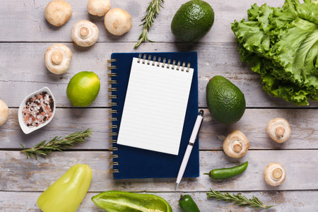 Blank notebook with fresh vegetables on white wooden tableの写真素材