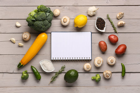 Blank notebook with fresh vegetables on white wooden tableの写真素材