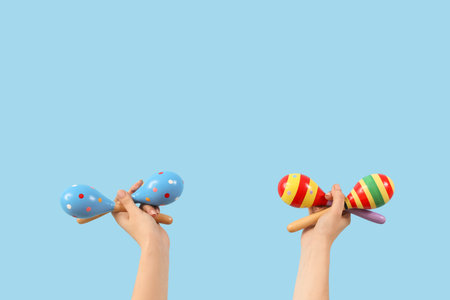 Female hands holding maracas on blue backgroundの写真素材