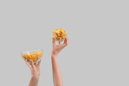 Female hands holding nachos on gray backgroundの写真素材