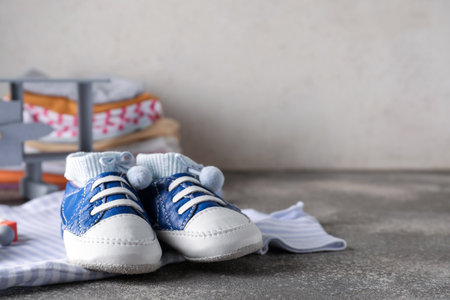 Pair of baby boots and clothes on grunge tableの写真素材
