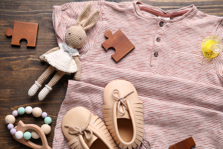 Composition with stylish baby bodysuit and accessories on wooden background, closeupの写真素材