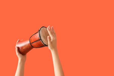 Female hands holding Mexican drum on orange backgroundの写真素材