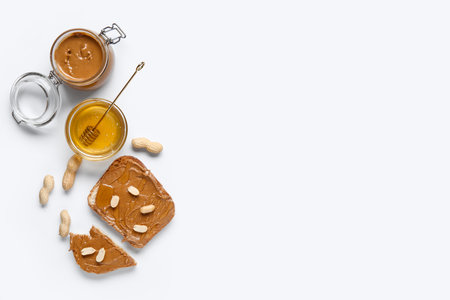 Toasts with peanut butter, nuts and bowl of honey on white backgroundの写真素材